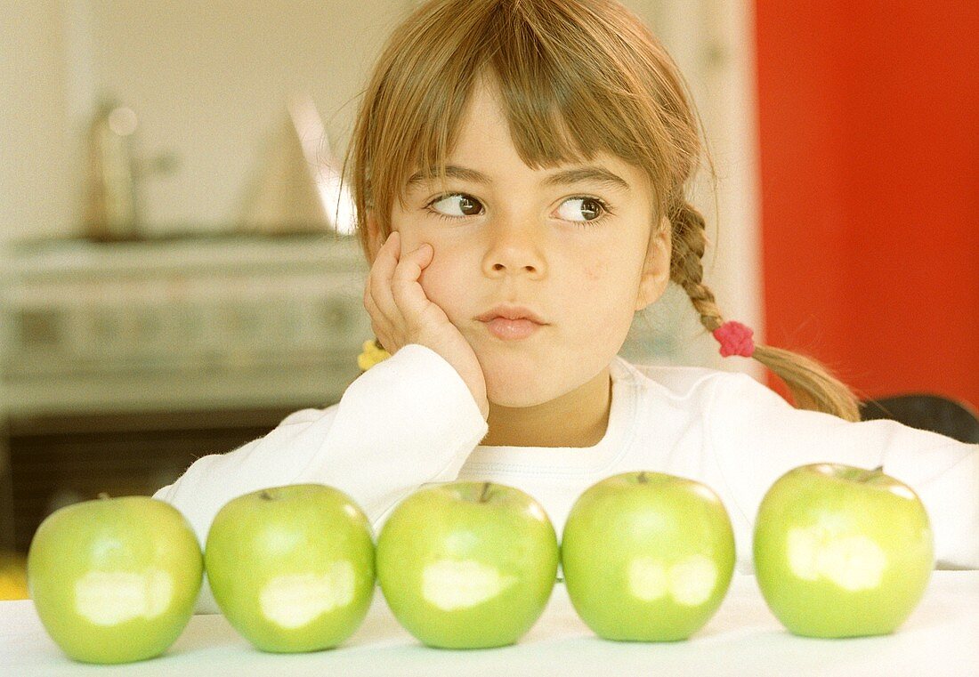 Mädchen vor angebissenen grünen Äpfeln