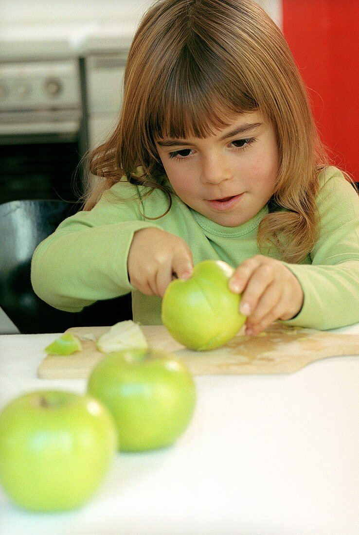 Mädchen schneidet grünen Apfel in Stücke