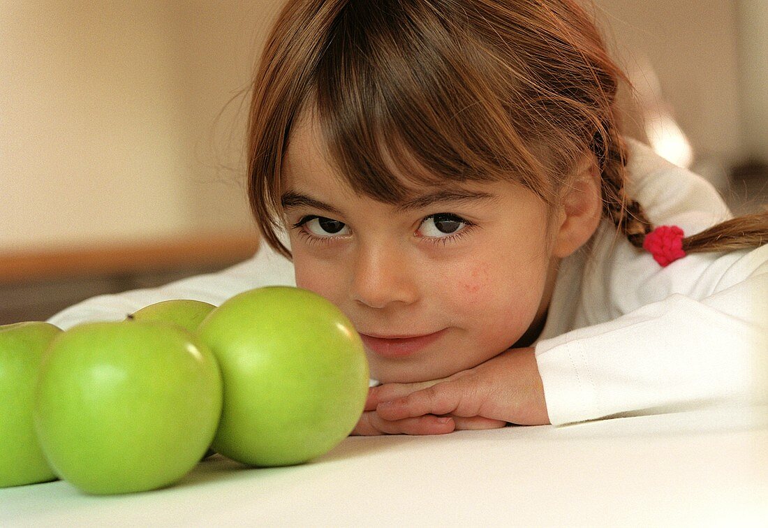 Kleines Mädchen neben grünen Äpfeln