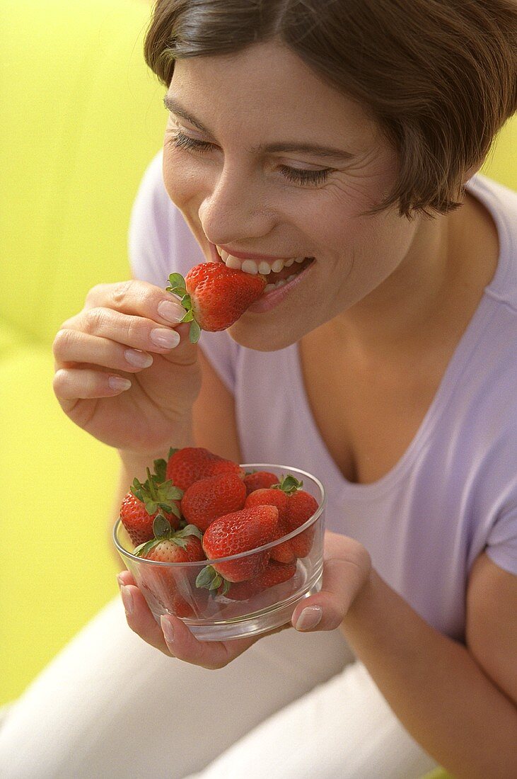 Young woman eating fresh strawberries (grainy effect)