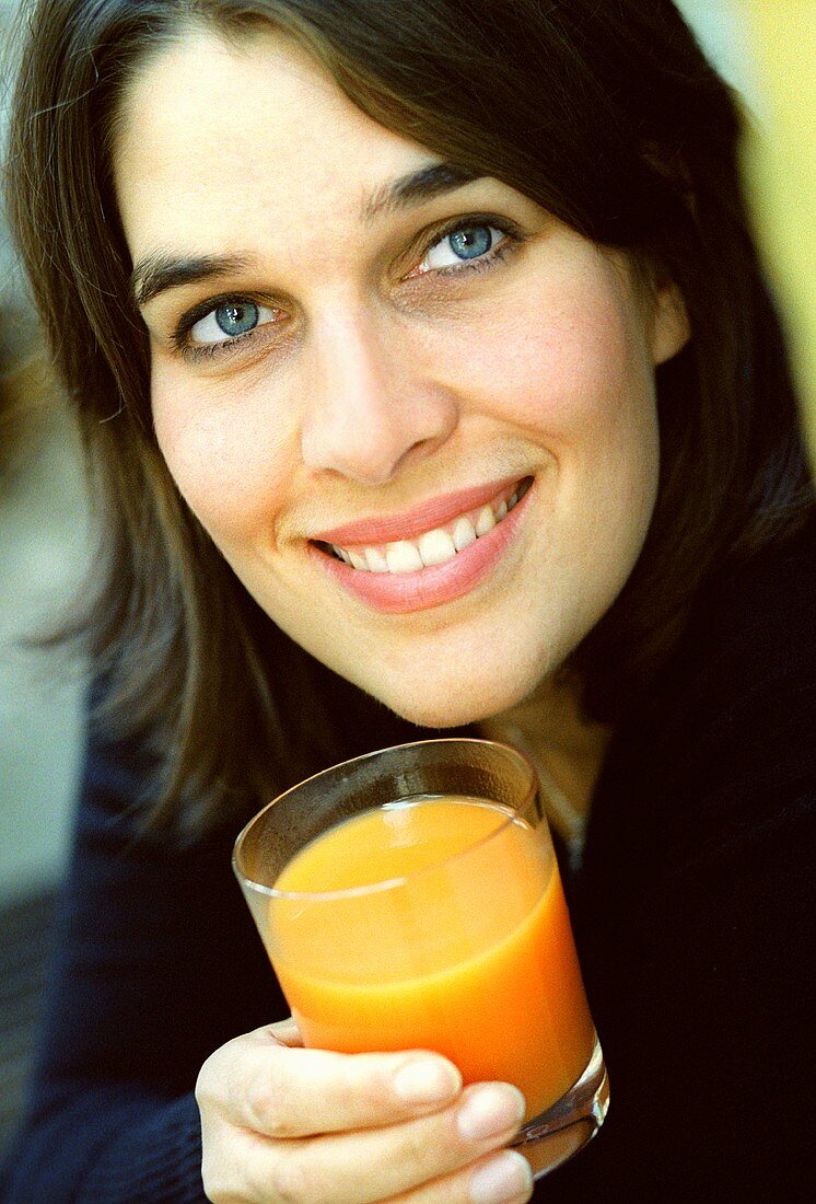 Young woman holding glass of carrot juice (grainy effect)