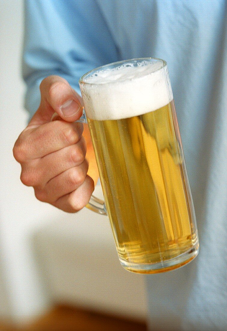 Hand hält Glas helles Bier