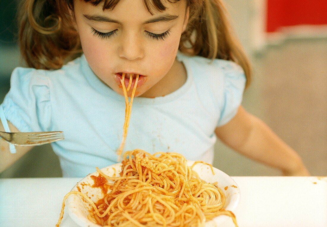 Mädchen isst Spaghetti mit Tomatensauce