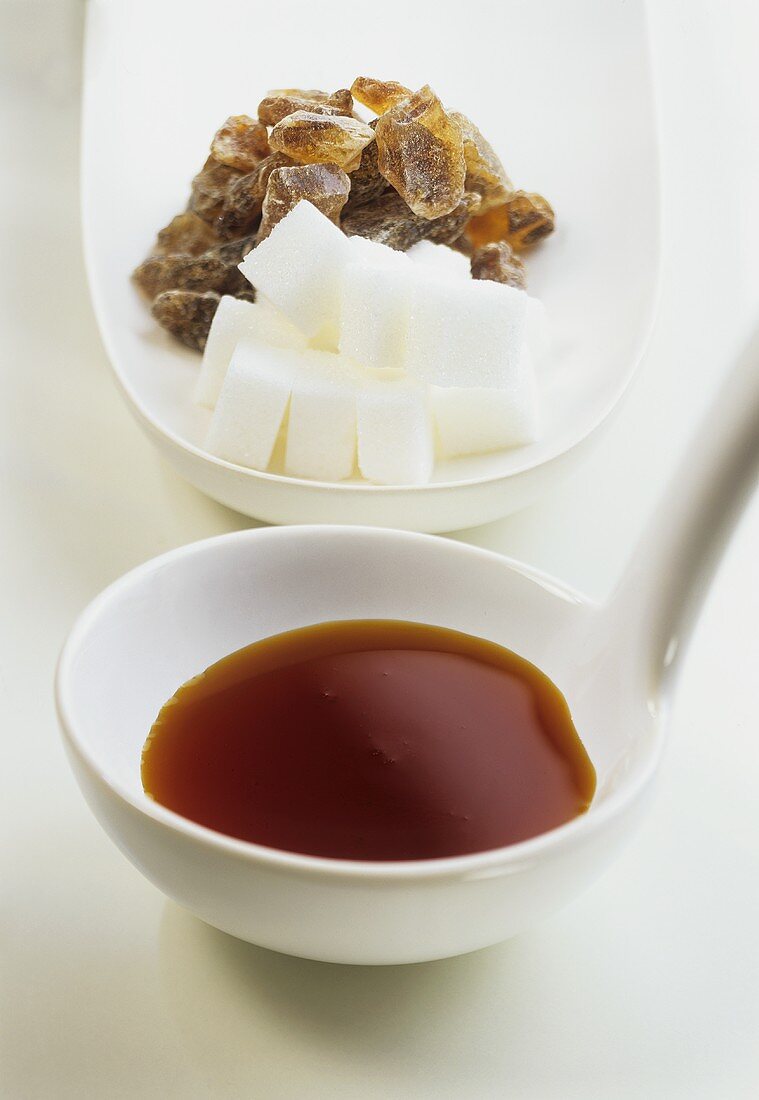 Caramel syrup on a ladle, sugar cubes and sugar crystals