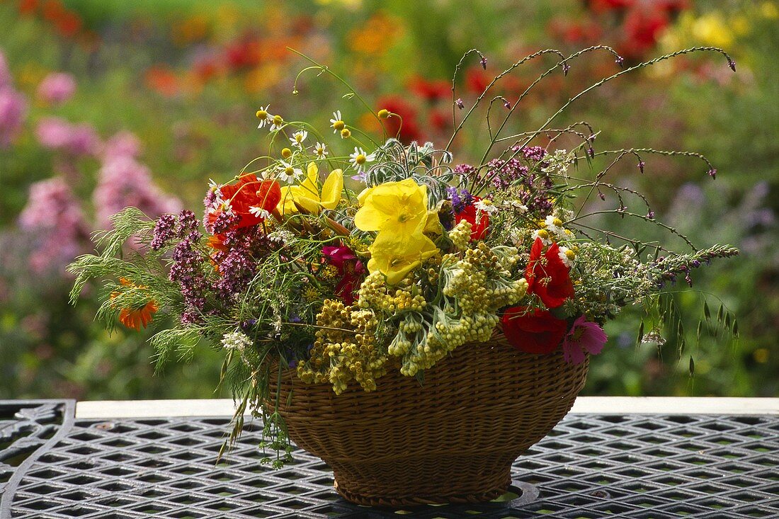 Summer arrangement of flowers and grasses in wicker bowl