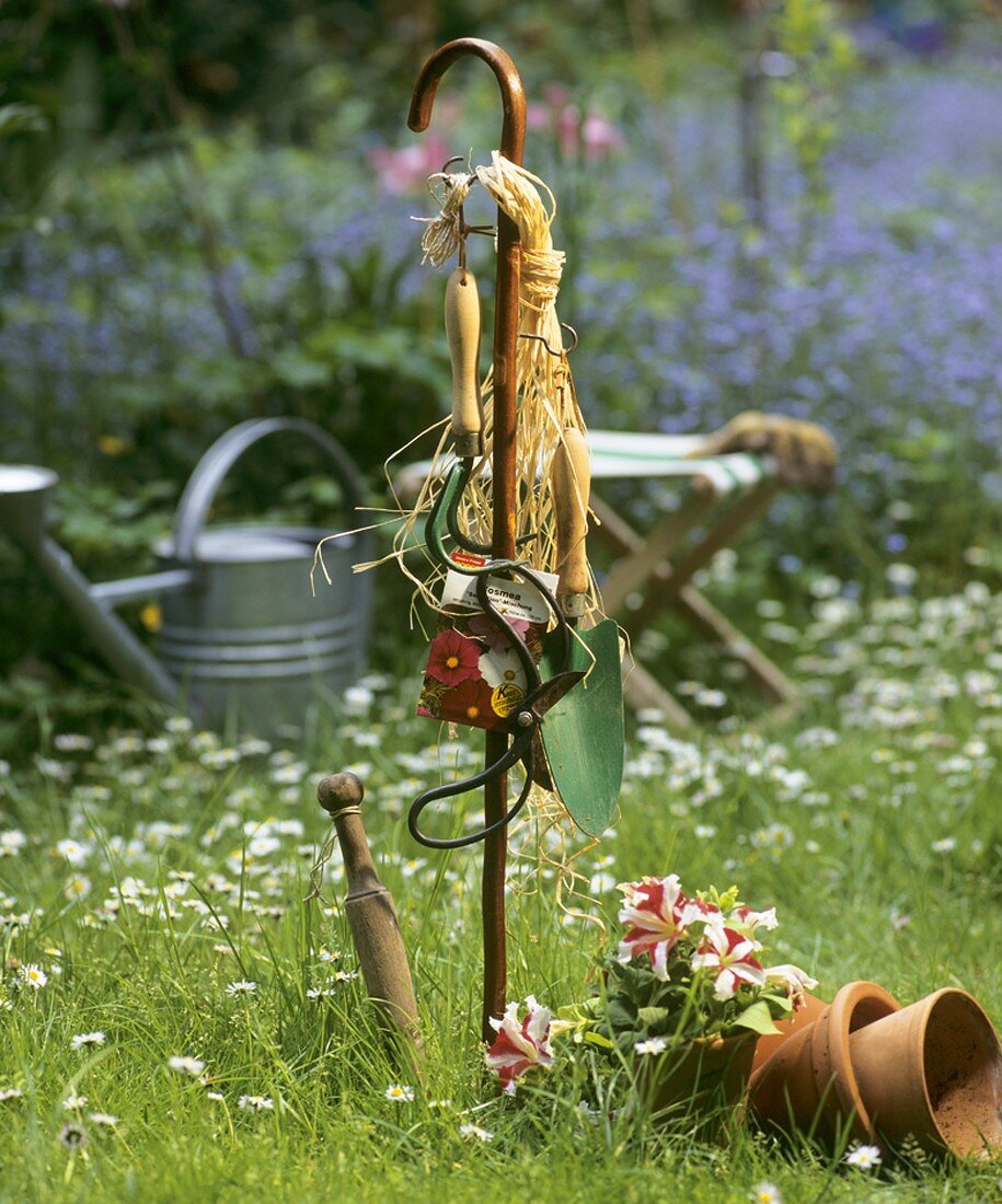 Garden tools hanging up on a stick on large lawn