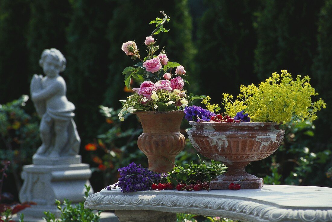 Blumen und Kirschen in Terracottapokalen arrangiert