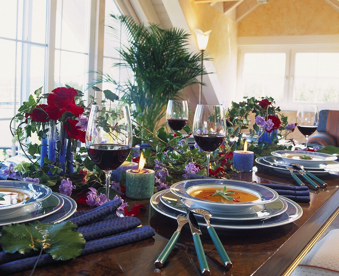 Table laid with soup, wine, roses and ivy