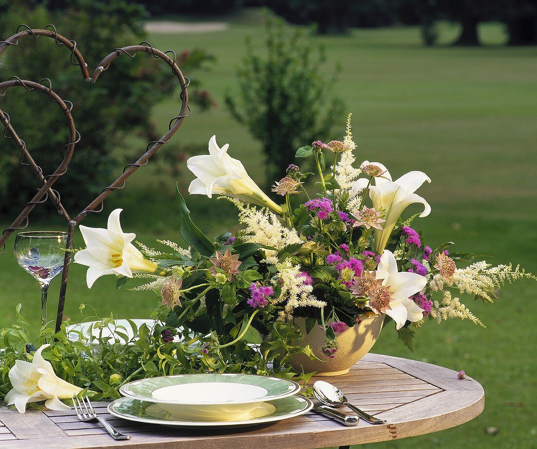 Laid table with arrangement of lilies, astilbe and Ageratum