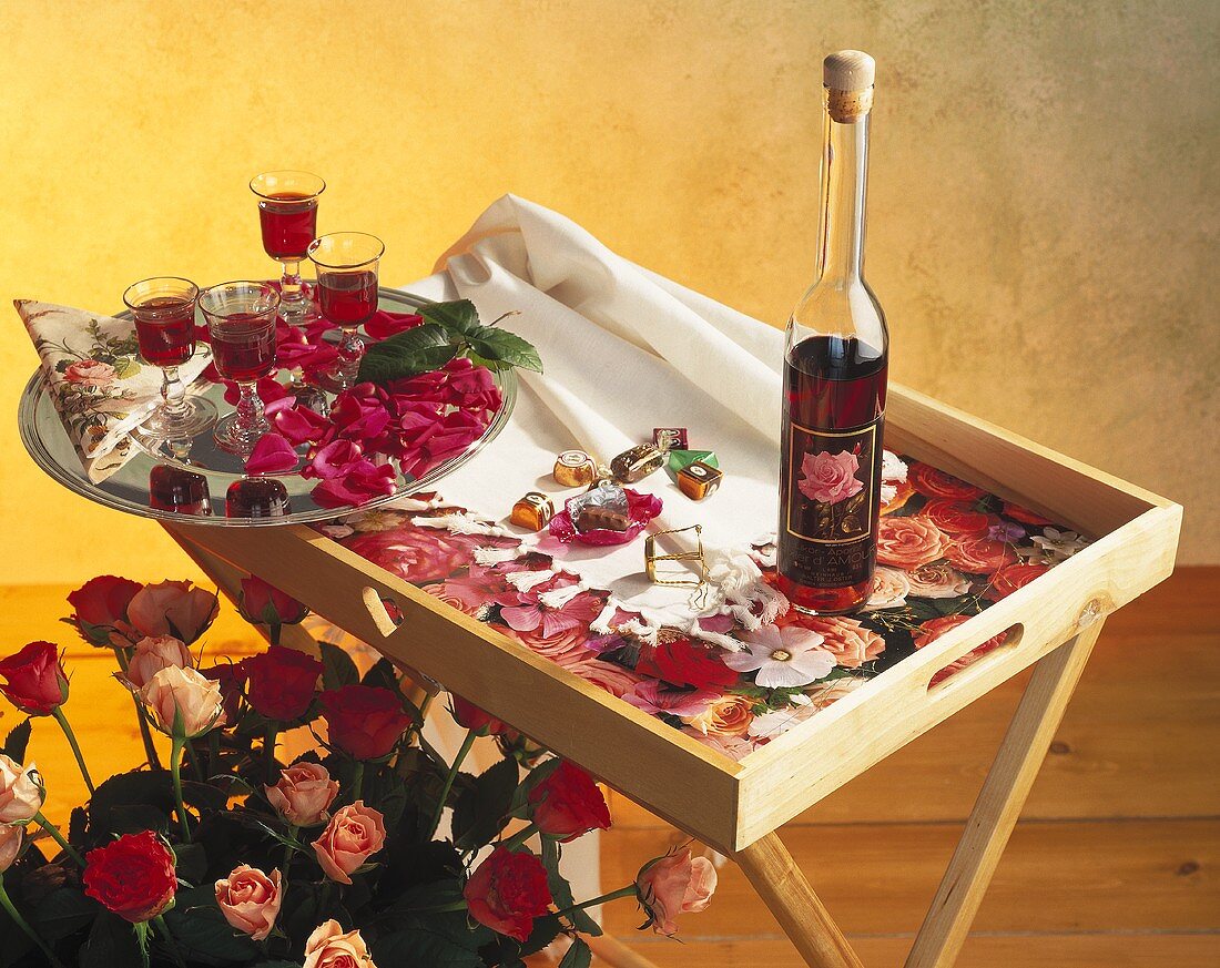 Bouquet of roses, bottle &  glasses of rose liqueur on tray