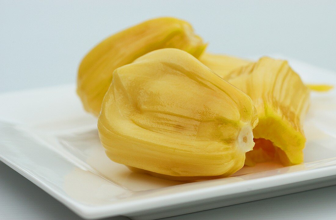 Four segments of a jackfruit on a white plate