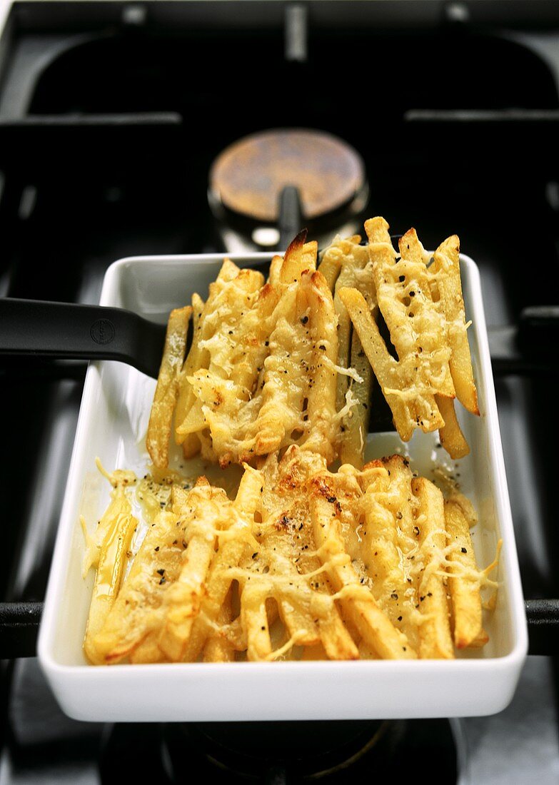 Chips with toasted Emmental topping on a gas cooker