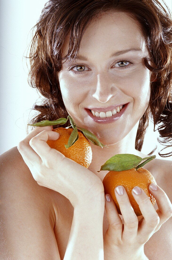 Junge Frau hält zwei Orangen in der Hand