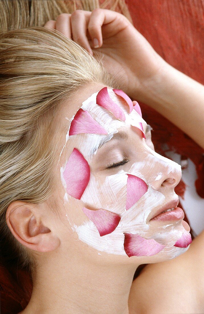 Blonde Frau trägt Gesichtsmaske mit Blüten im Gesicht