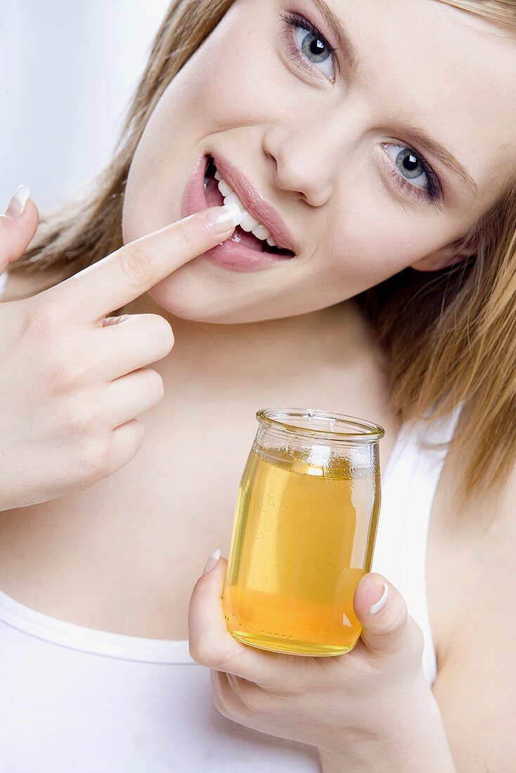 Young woman rubbing honey into her lips