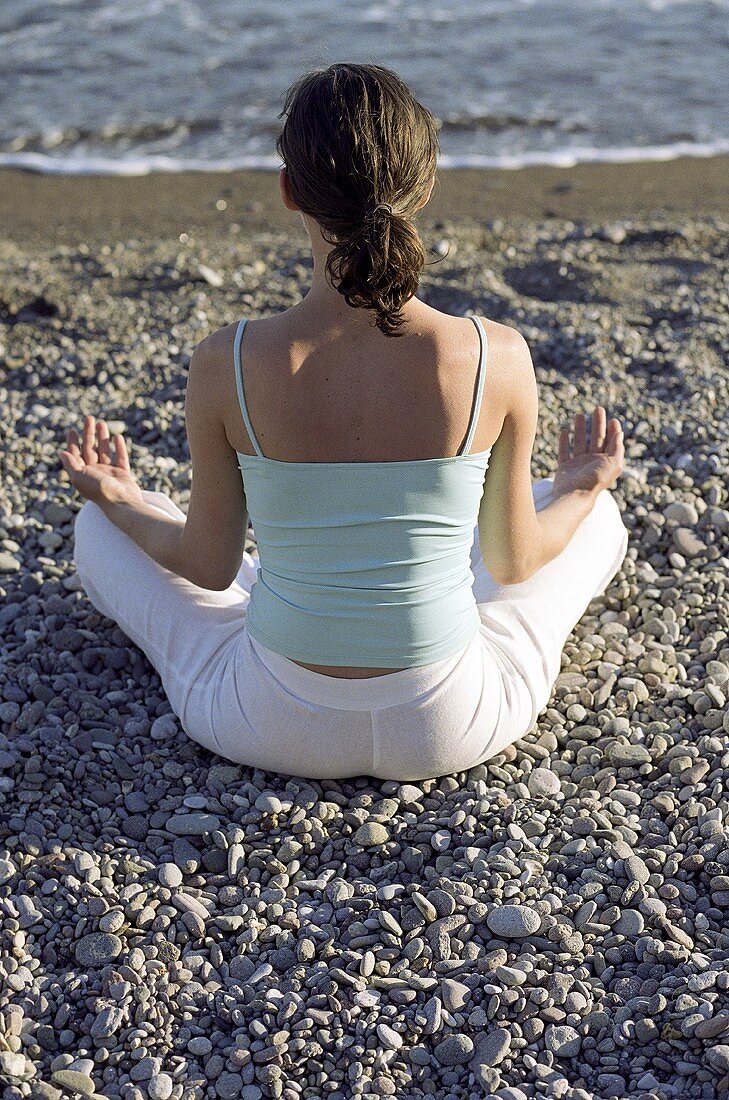 Junge Frau beim Meditieren am Strand