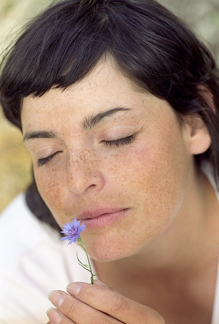 Young woman smelling a cornflower