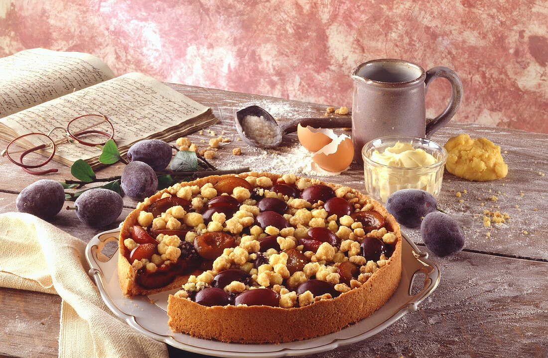 Plum cake with cookery book and baking ingredients