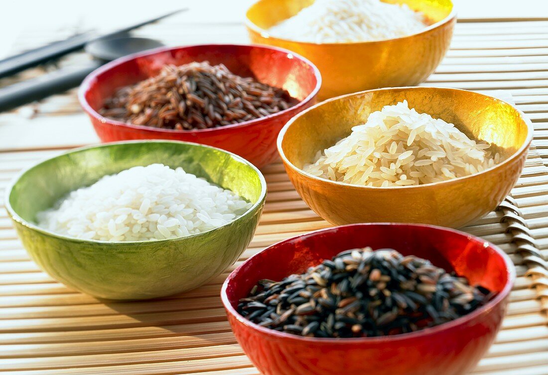 Several types of rice in five coloured bowls