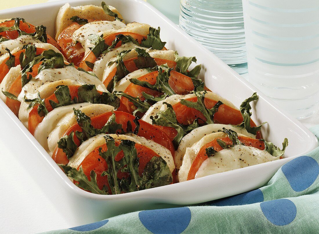 Baked bread dish with tomatoes, mozzarella and rocket