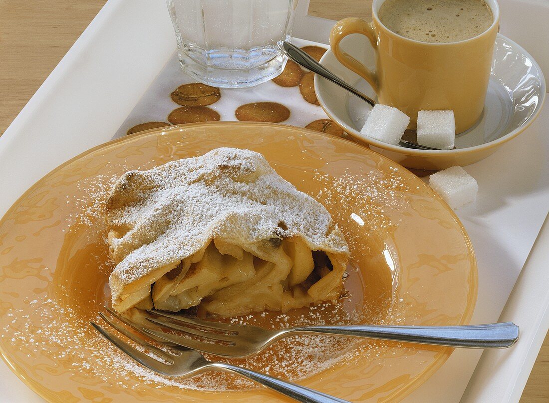 Piece of Viennese apple strudel with icing sugar, with coffee