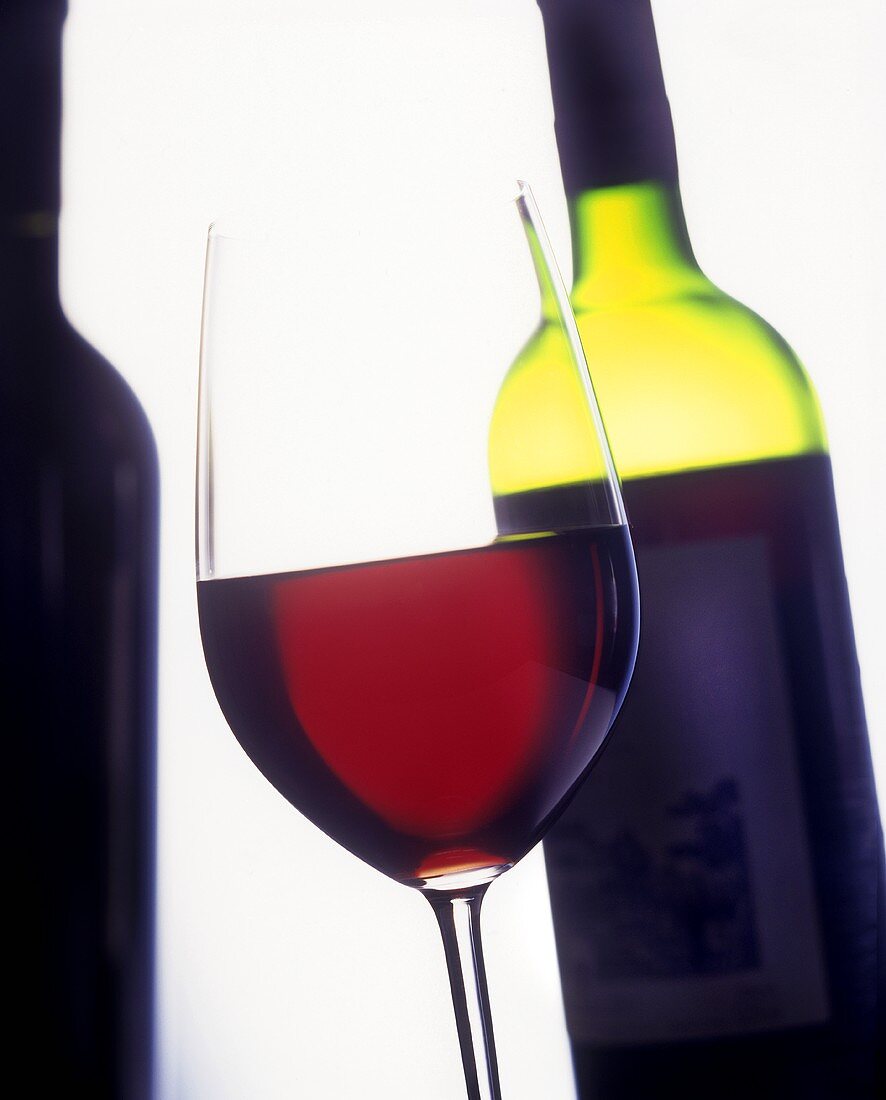 Ein Glas Rotwein mit einer Flasche im Hintergrund