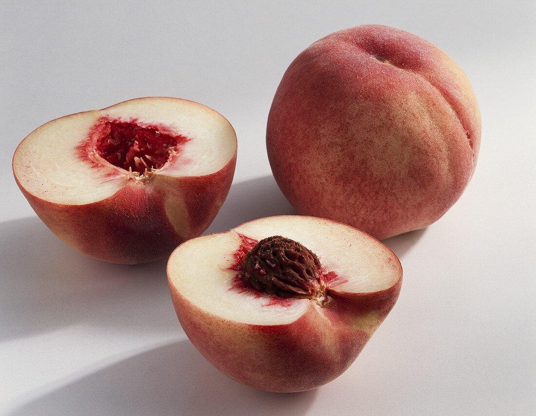Peaches (Prunus persica), variety 'Honora', whole & halved