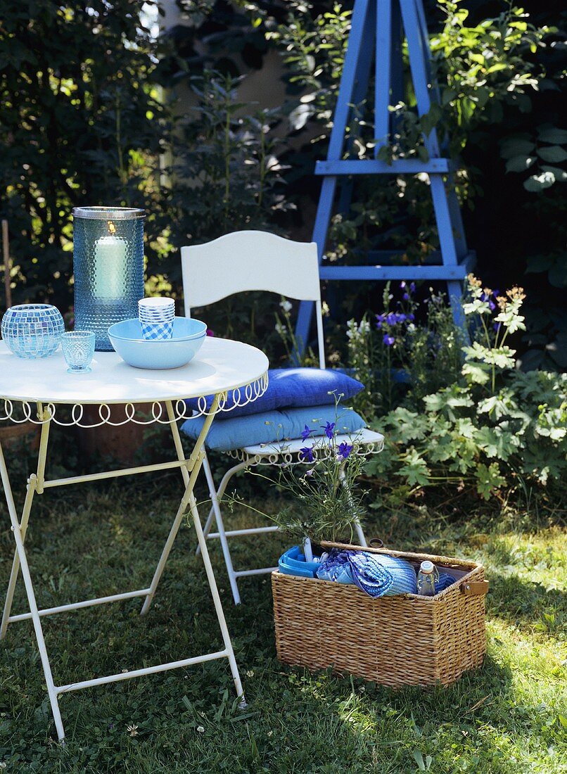 Garden furniture and a picnic basket in grass