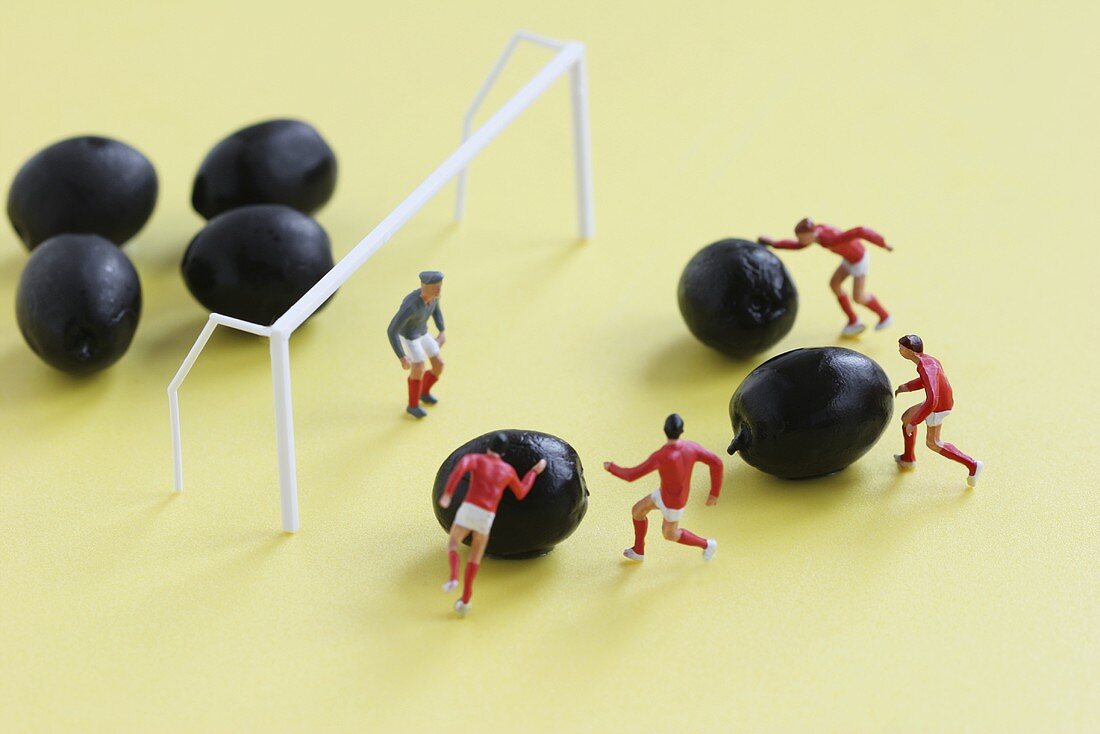 Miniature footballers attacking the goal with olives