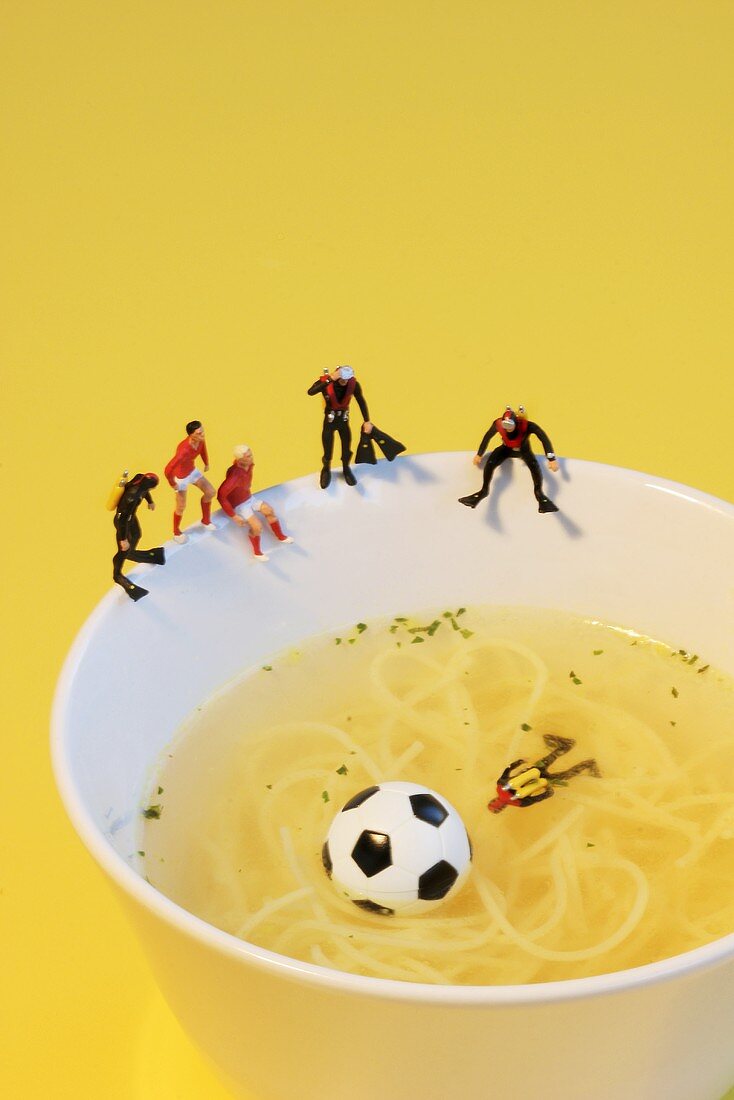 Footballers looking for ball in noodle soup pond