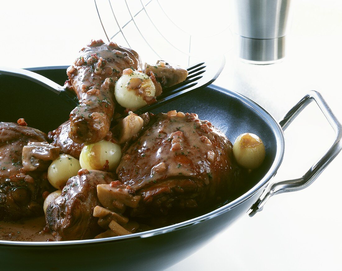 Coq au vin mit Perlzwiebeln und Champignons im Wok