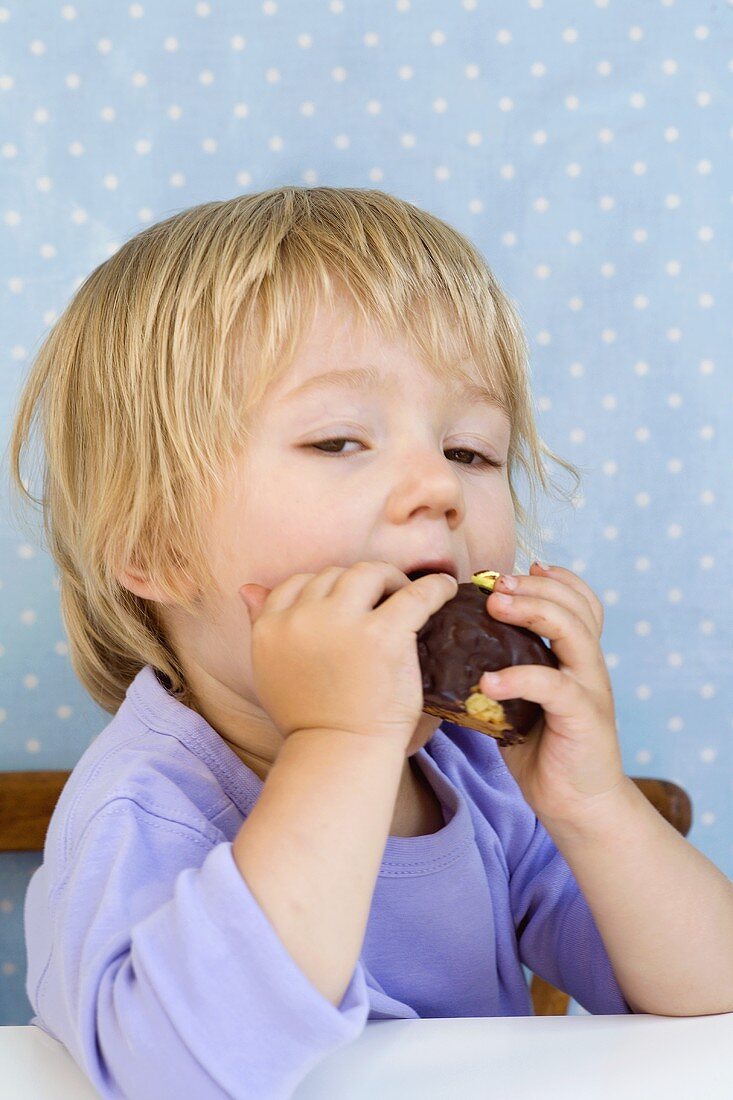Small boy biting into a small chocolate cake