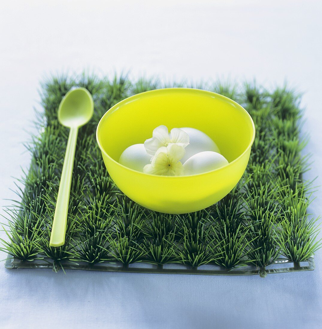 Eggs with flowers in a plastic bowl on artificial grass