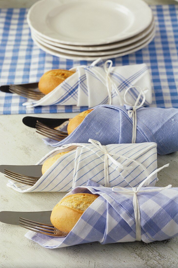 Four sets of cutlery and bread rolls tied in napkins