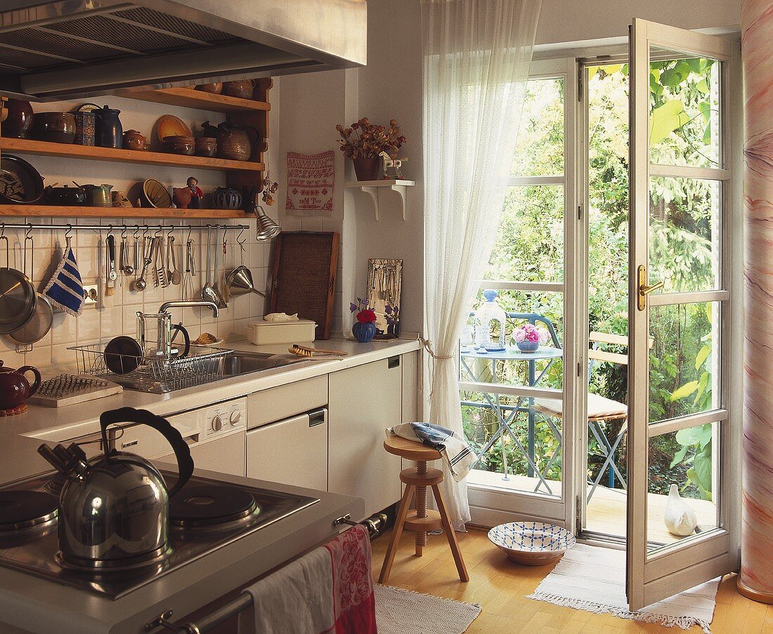 Blick von der Küche durch offene Glastür auf kleine Terrasse
