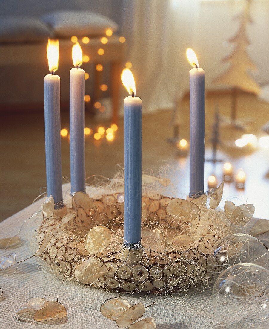 Christmas wreath made of wooden discs with 4 pale-blue candles