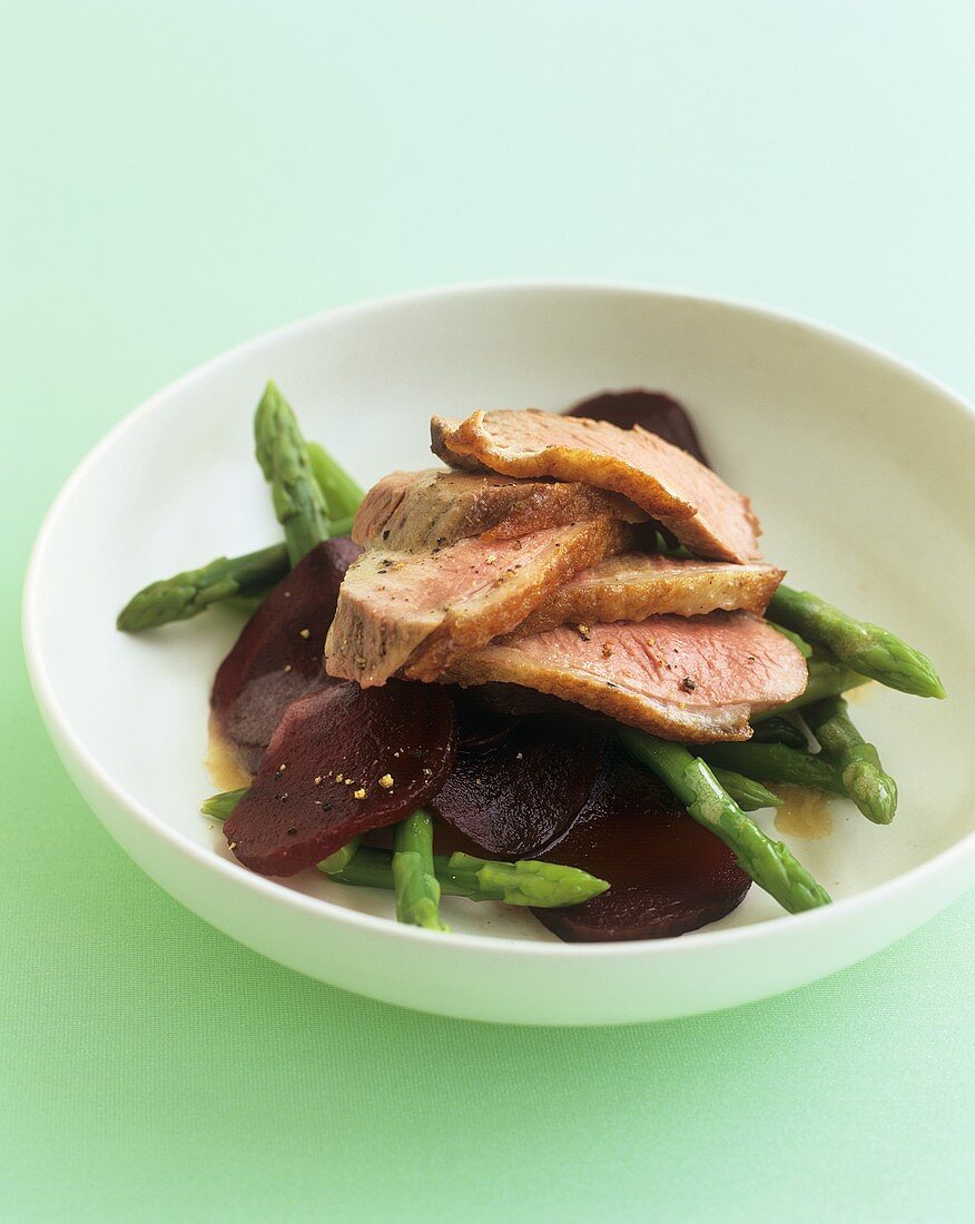 Duck in orange sauce on green asparagus and beetroot