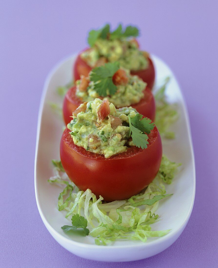 Three tomatoes stuffed with avocado and salad