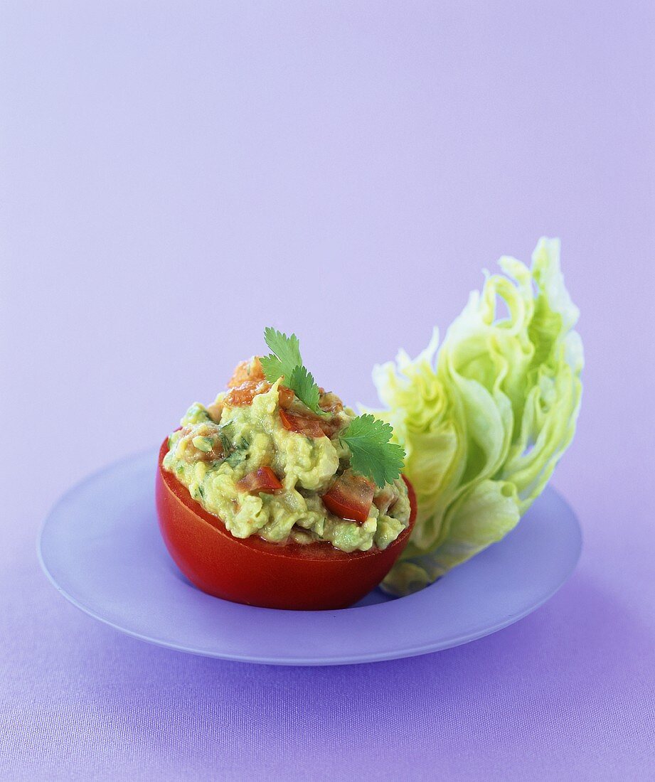 A tomato stuffed with avocado and salad
