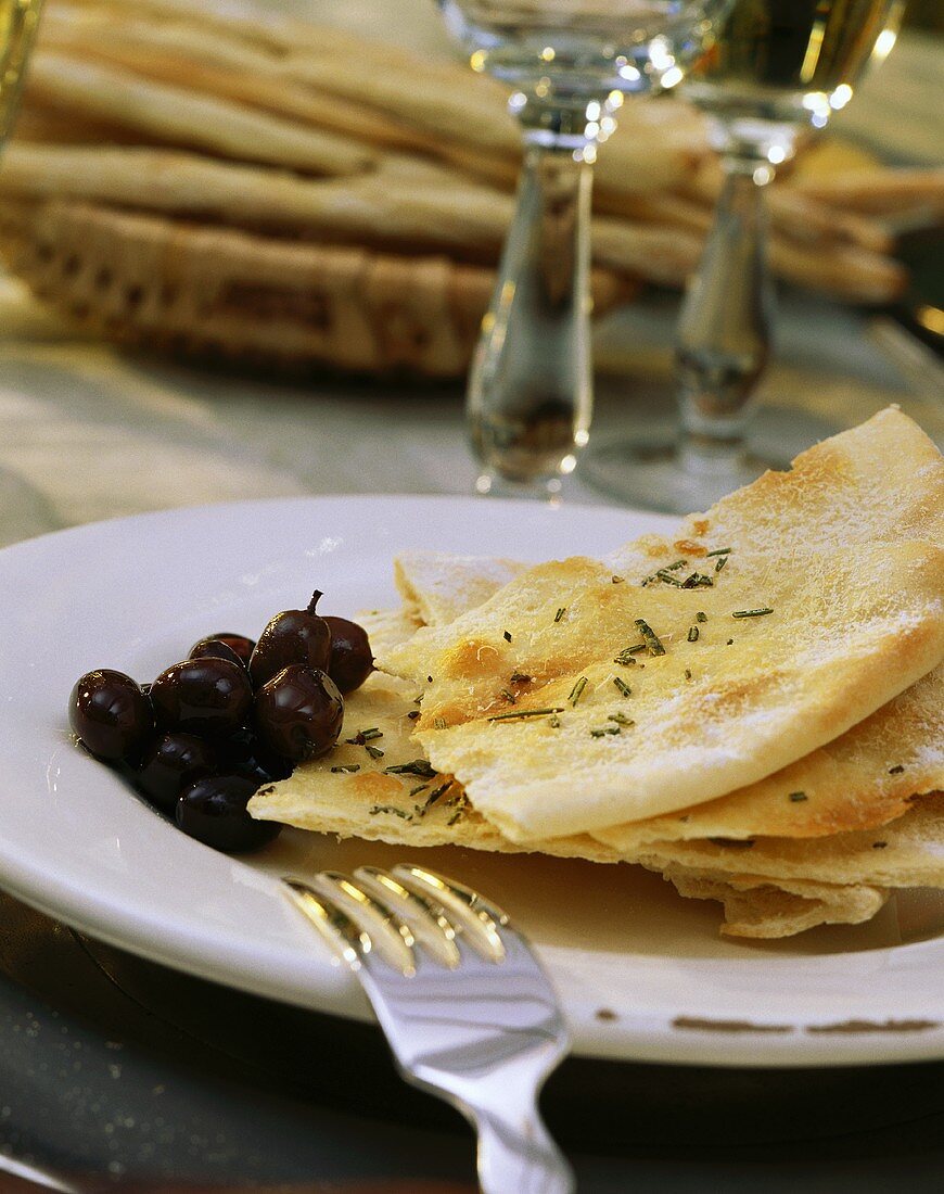 Black olives & flat bread on plate on laid table