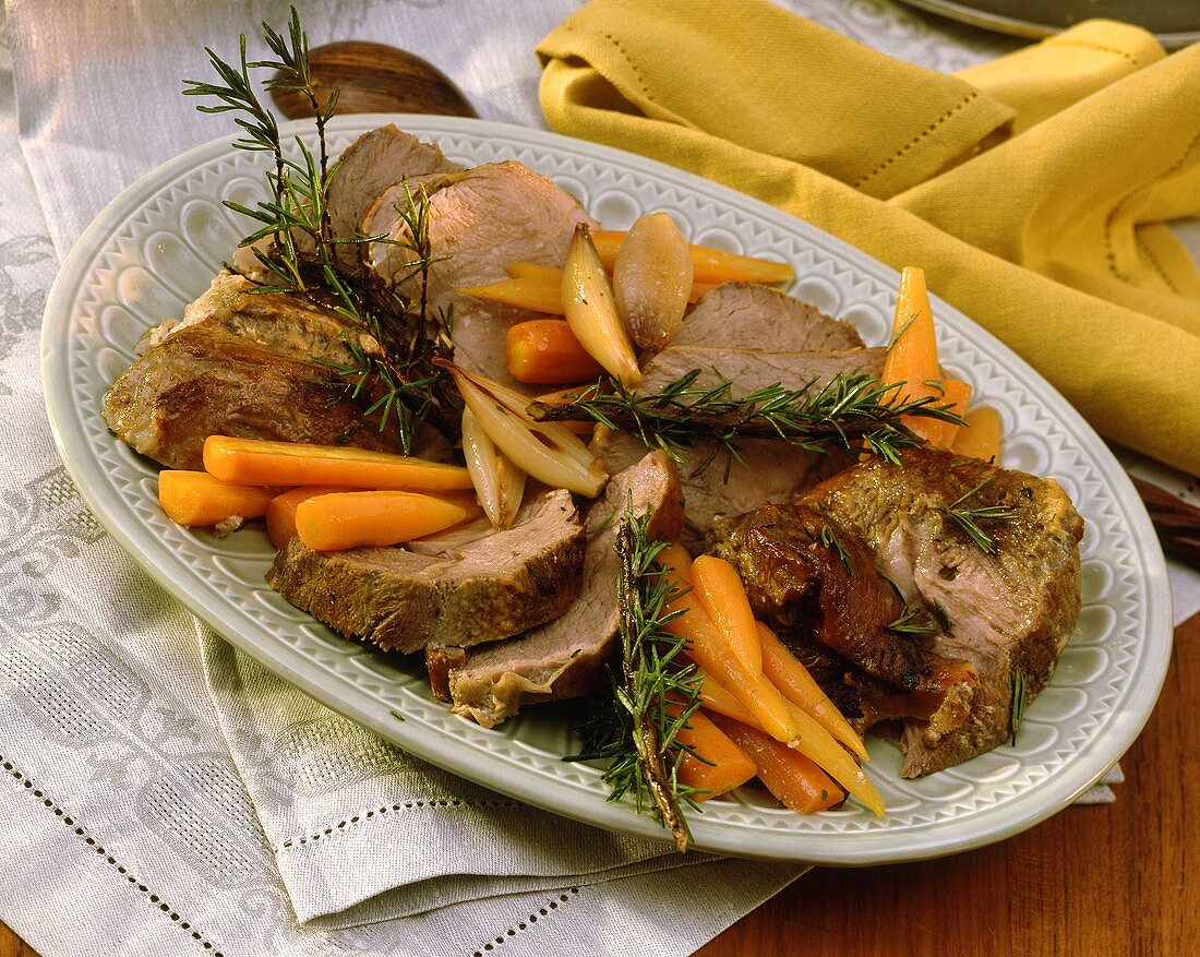 Pieces of roast veal with rosemary, carrots, garlic on plate
