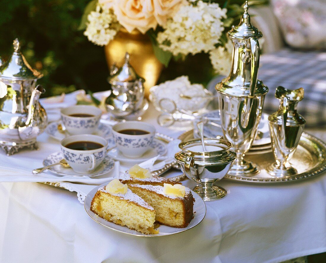 Elegant summery table laid for coffee in garden