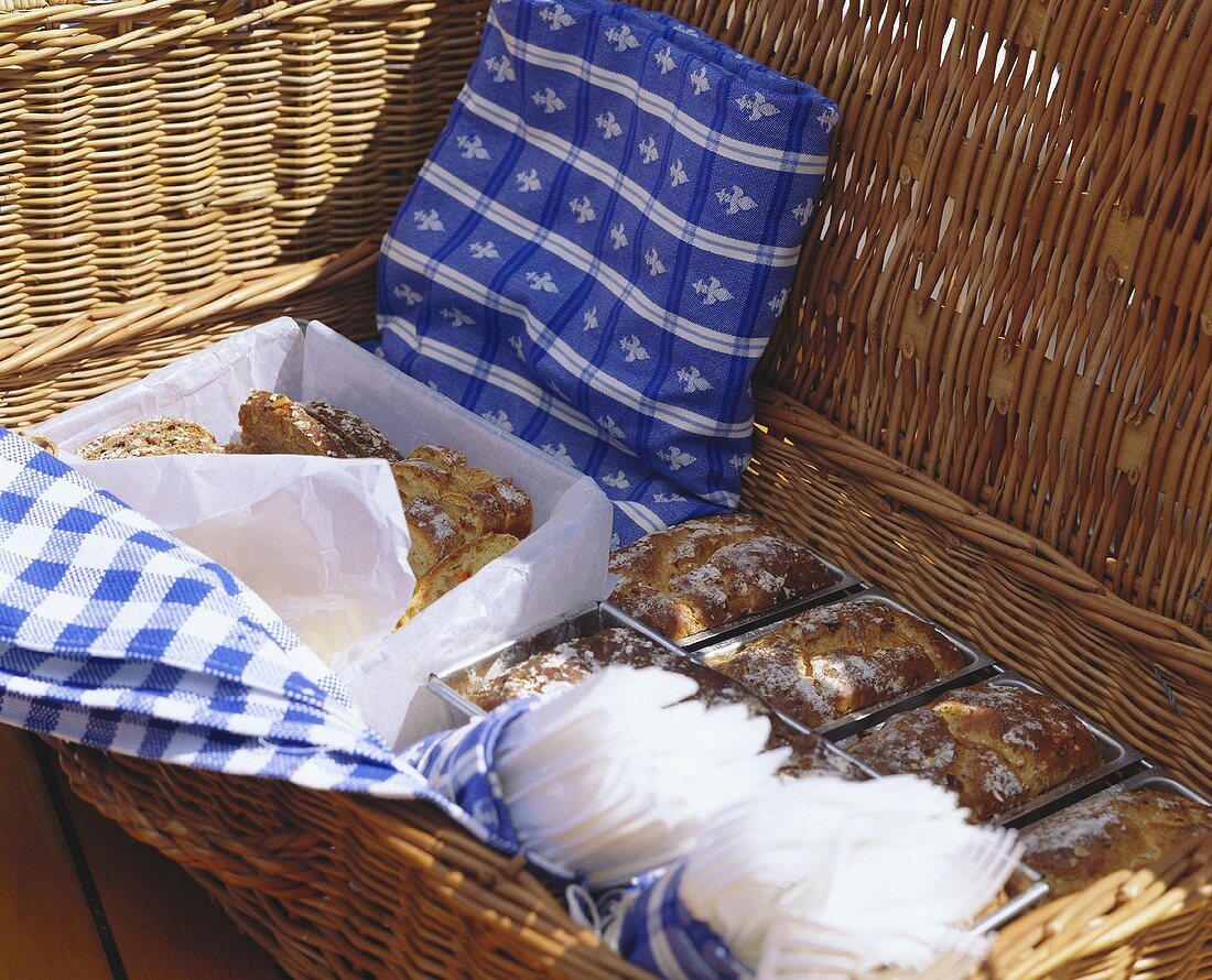 Picnic basket with various breads, cakes & plastic cutlery