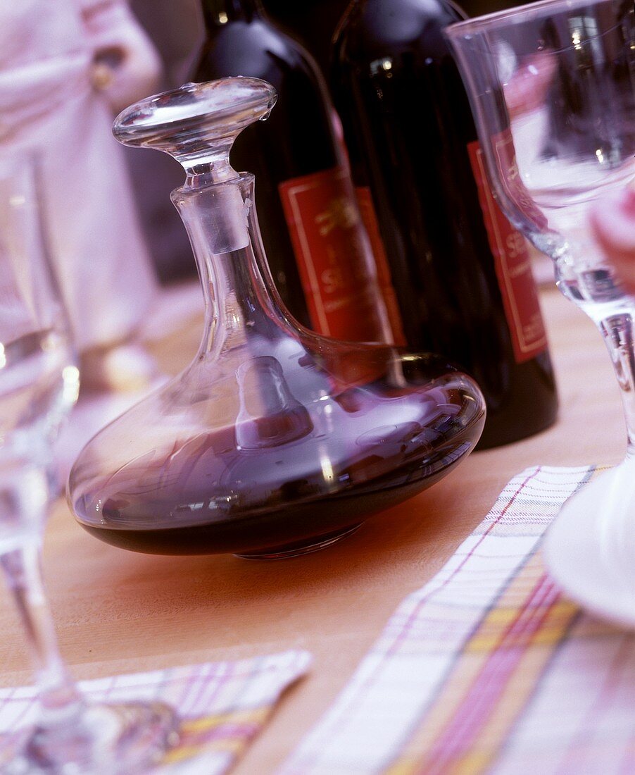 Red wine bottles, carafe and glasses on laid table