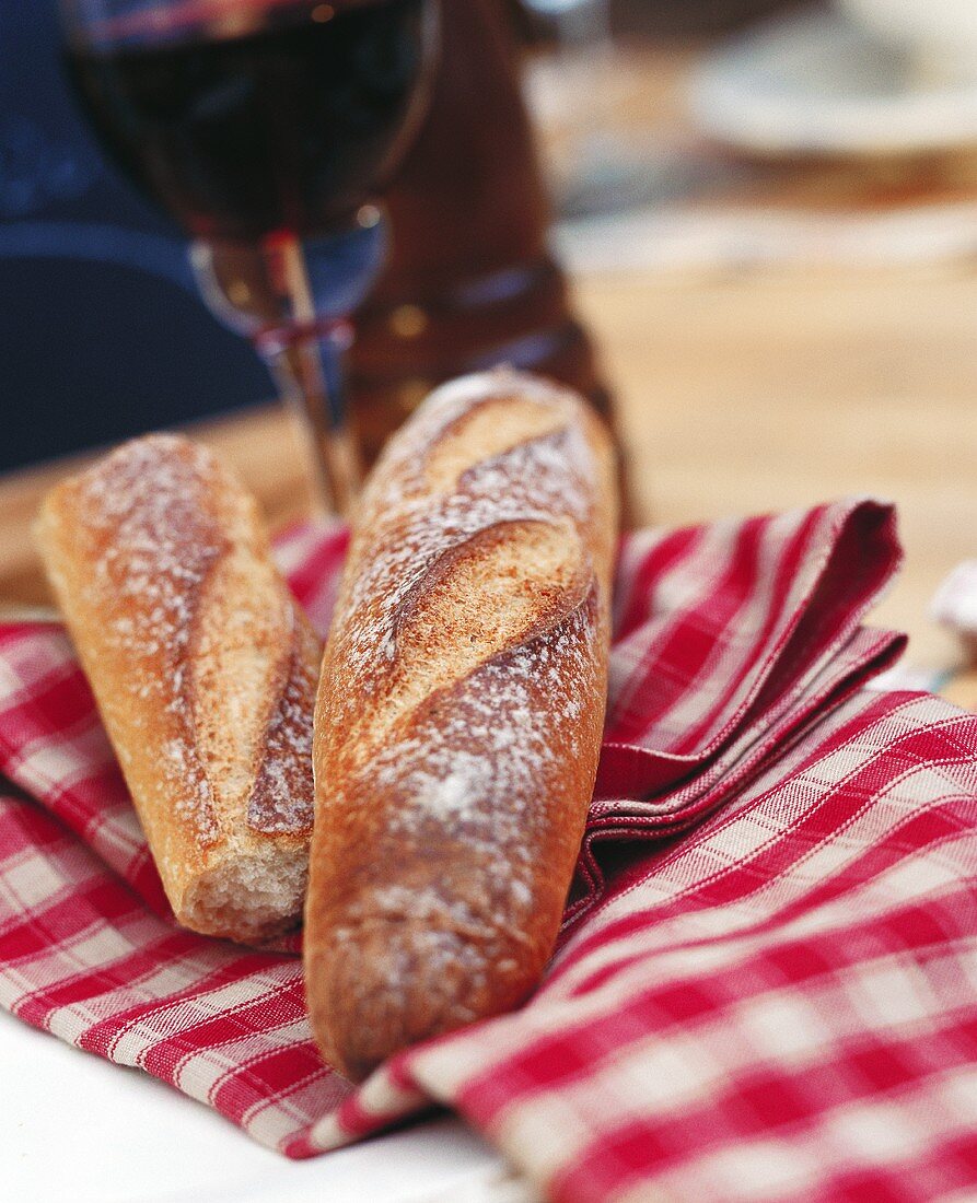 Baguette auf rot-weiss-karierter Serviette & Glas Rotwein