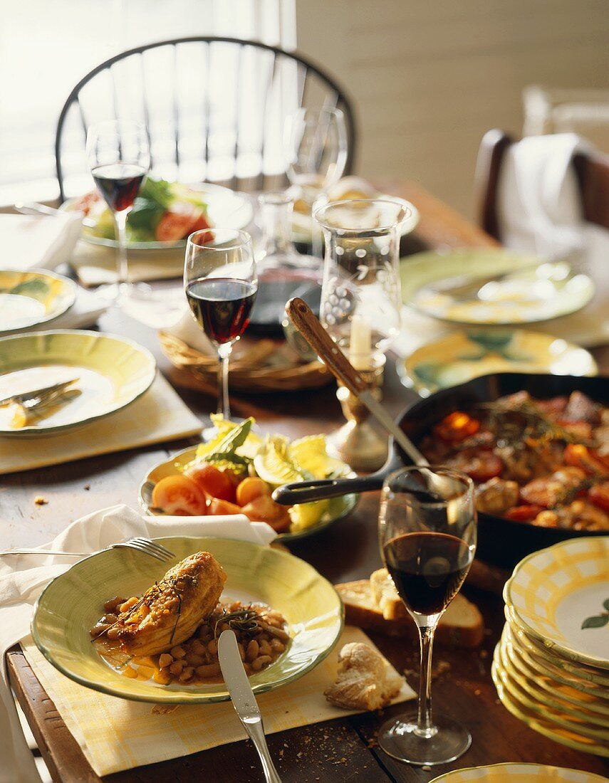 Rustikal gedeckter Tisch mit mediterranen Speisen & Rotwein