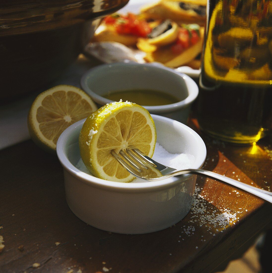Halbe Zitrone in Schälchen mit Salz eintauchen