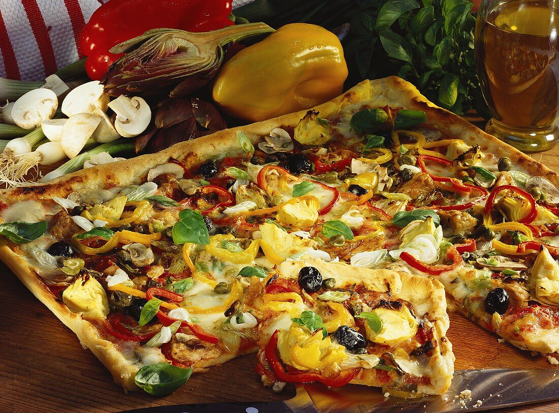 Bunt belegte Blechpizza mit Paprika, Artischocken & Oliven