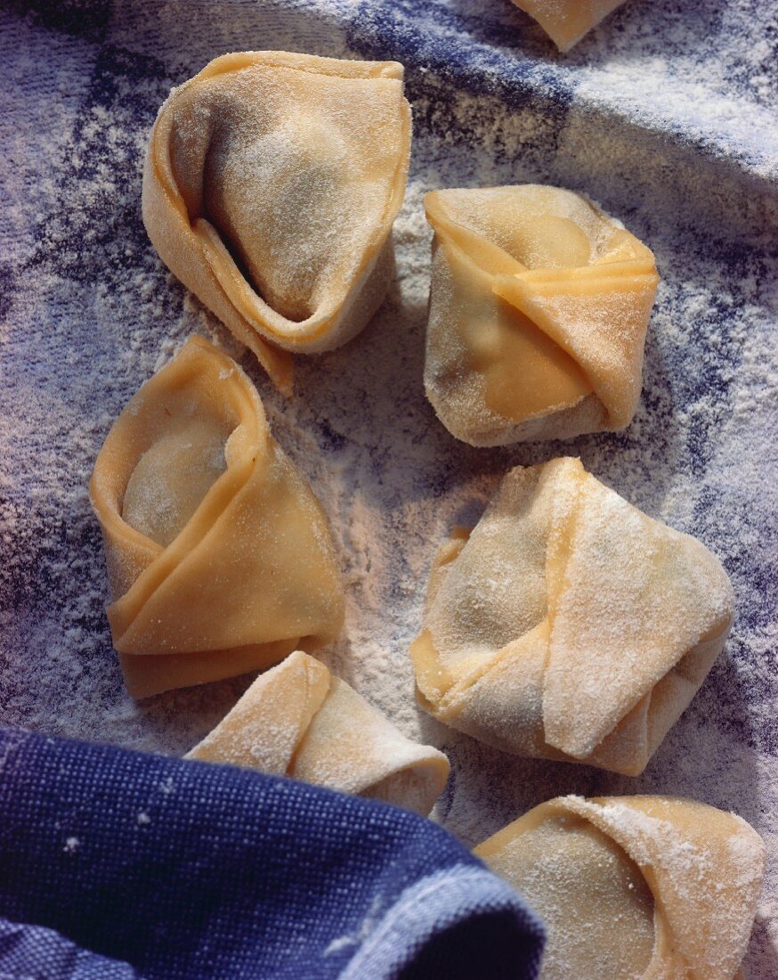 Handgemachte, gefüllte Tortellini auf Tuch mit Mehl