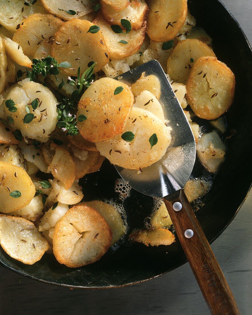 Fried potatoes with herbs and caraway in the pan 